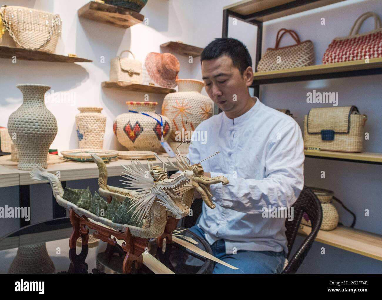 Zigui, China's Hubei Province. 11th June, 2021. A man makes dragon-boat-shaped handicrafts to mark the upcoming Duanwu, or the Dragon Boat Festival in Zigui, central China's Hubei Province, June 11, 2021. Duanwu, or the Dragon Boat Festival, is traditionally celebrated on the fifth day of the fifth month on the Chinese lunar calendar in memory of the death of famous Chinese poet Qu Yuan from the Warring States Period (475-221 B.C.). Zigui County is regarded as the hometown of Qu Yuan. Credit: Xiao Yijiu/Xinhua/Alamy Live News Stock Photo