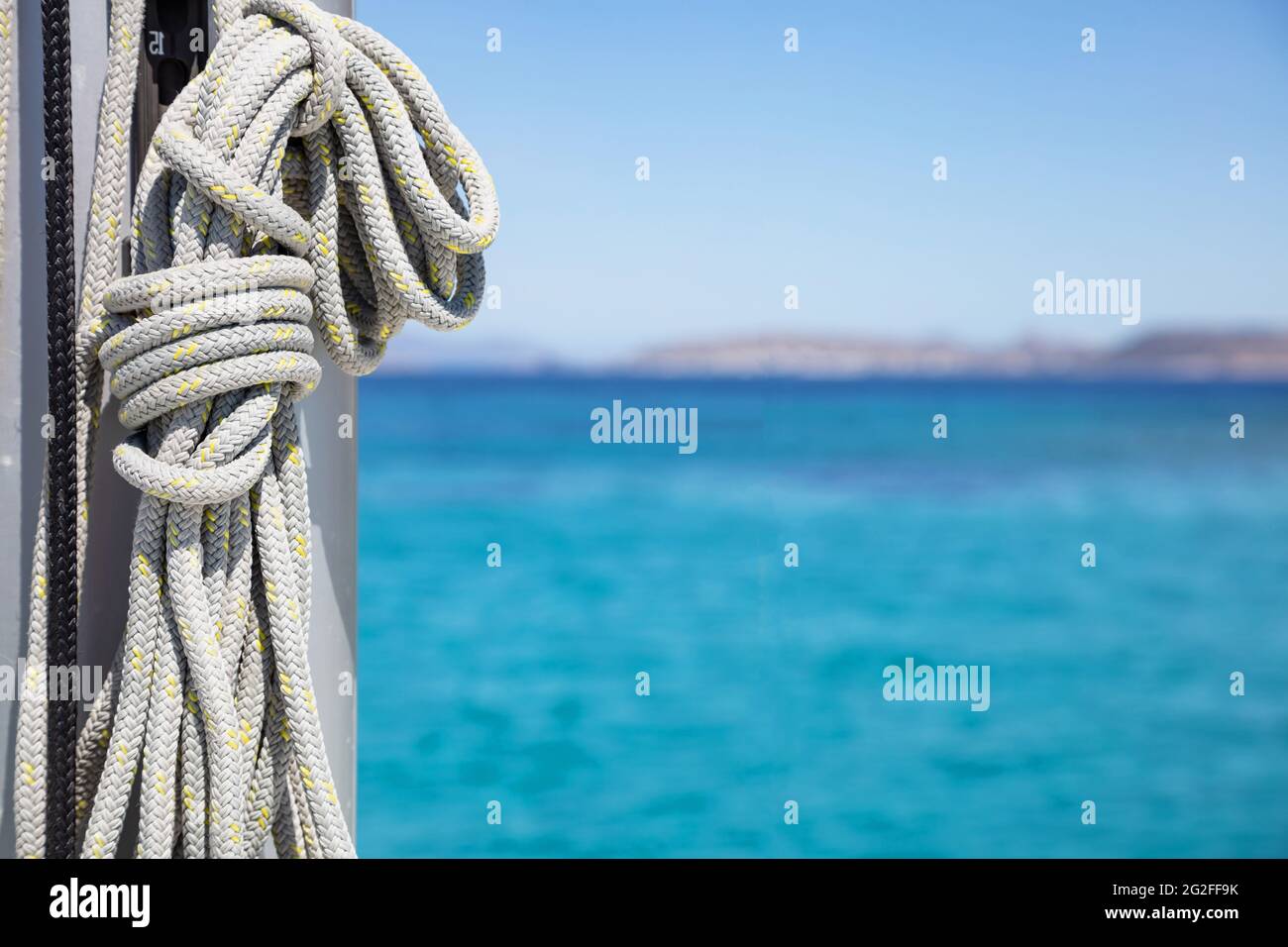 Sailboat equipment, Yachting rope tied to the ship mast. Mooring ropes on the sailing boat, blur seascape background. Closeup view, copy space. Sailbo Stock Photo