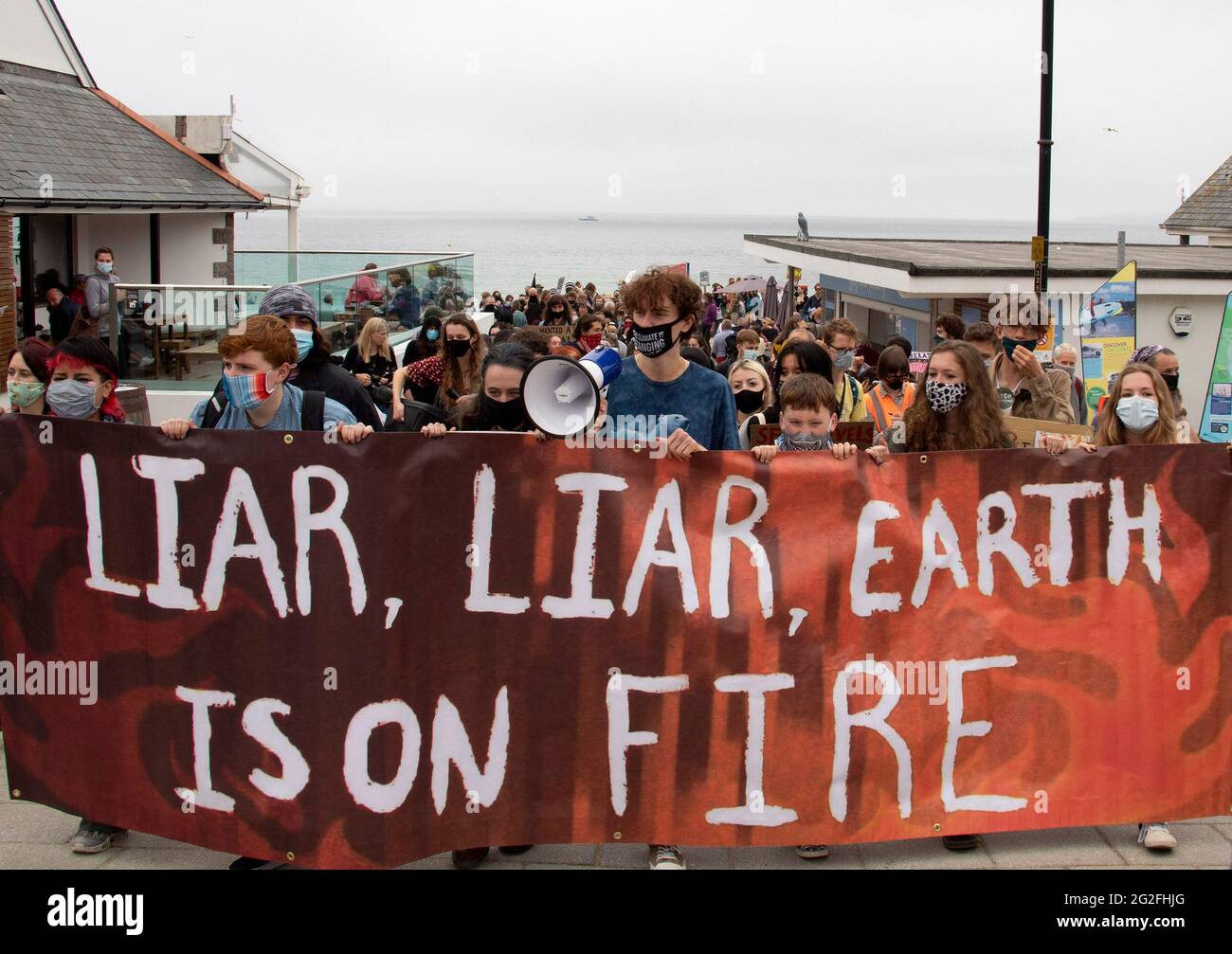 Cornwall, UK. June 11 2021: A group of protesters march off Gyllyngvase beach and into Falmouth, Cornwall, as part of the Youth Strike for Climate, ahead of the G7 summit happening at the weekend. 11th June 2021. Anna Hatfield/Pathos Credit: One Up Top Editorial Images/Alamy Live News Stock Photo