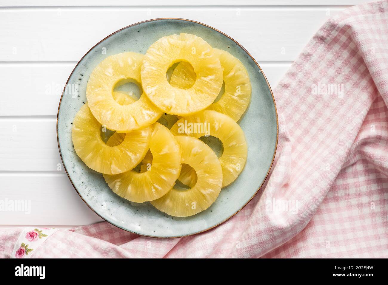 Canned sliced pineapple fruit on plate. Top view. Stock Photo