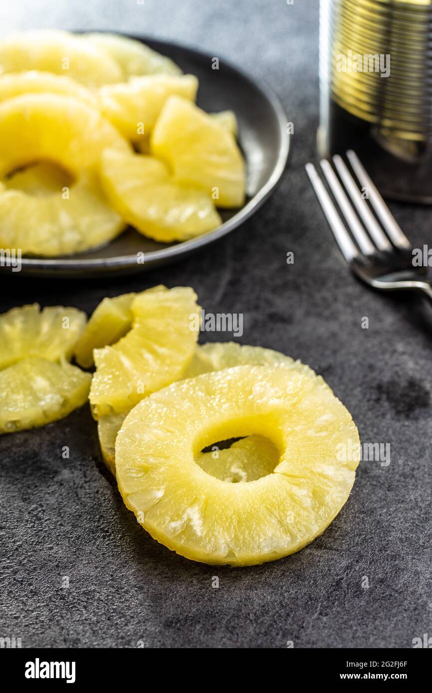Canned sliced pineapple fruit on black table. Stock Photo