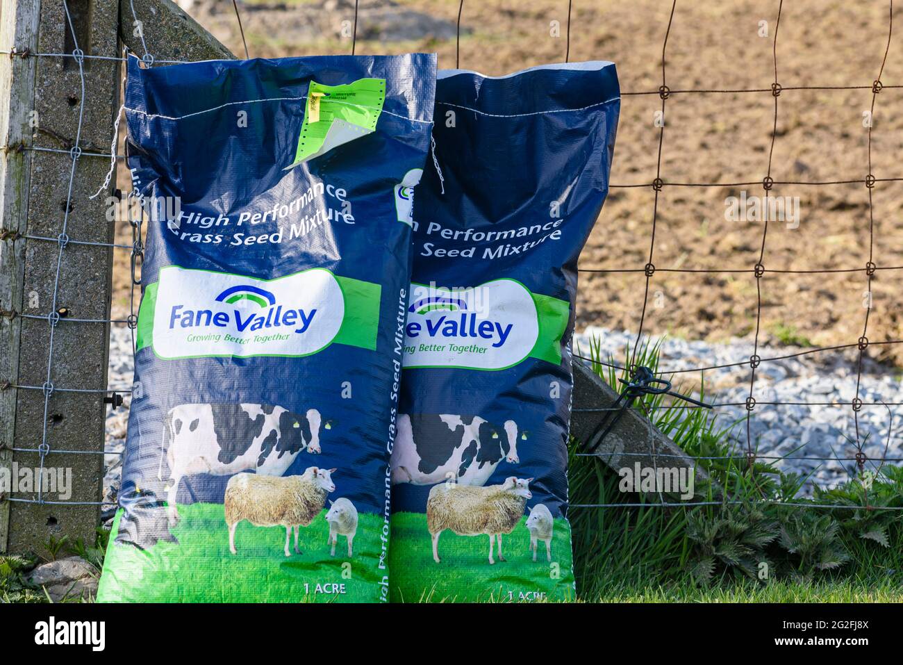 Two bags of farmland field grass seed waiting to be sown at a farm. Stock Photo