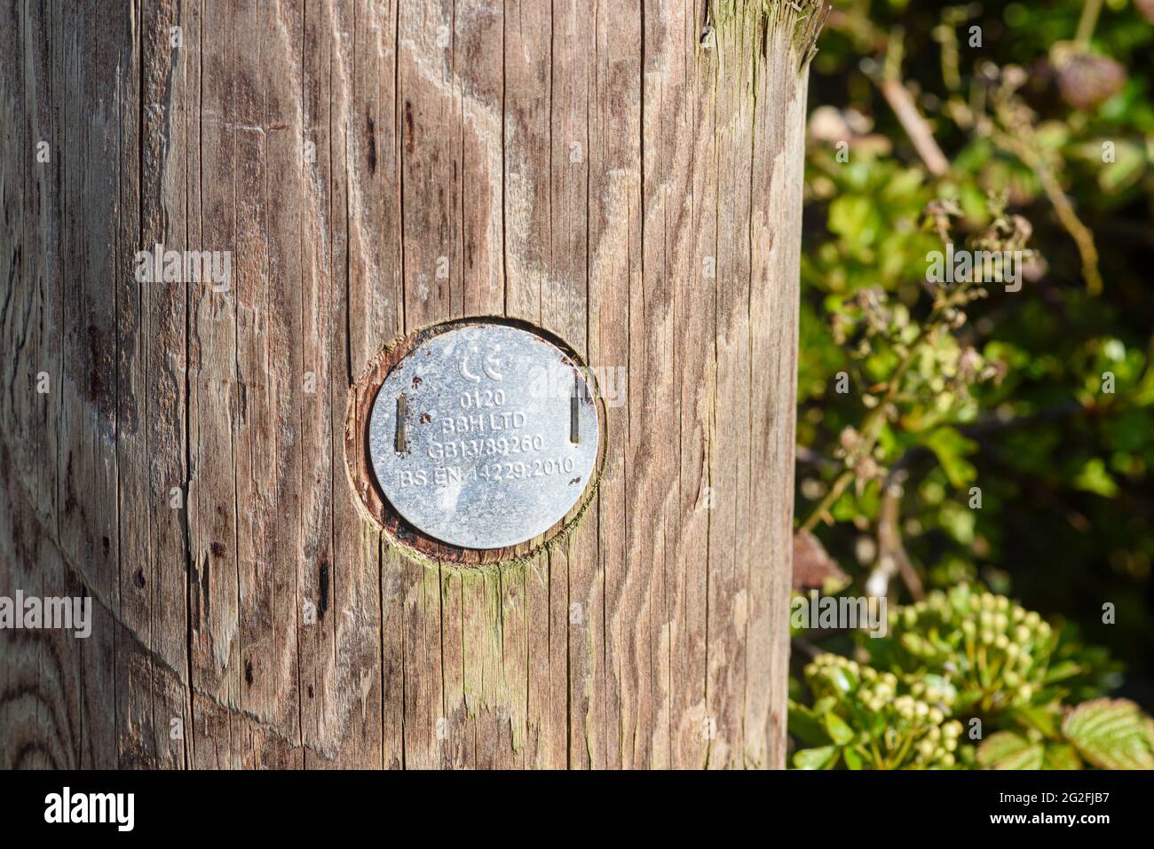 Metal plaque with a CE marking on a wooden telegraph pole, indicating it meets European Union legislation for safety, health and environmental protect Stock Photo