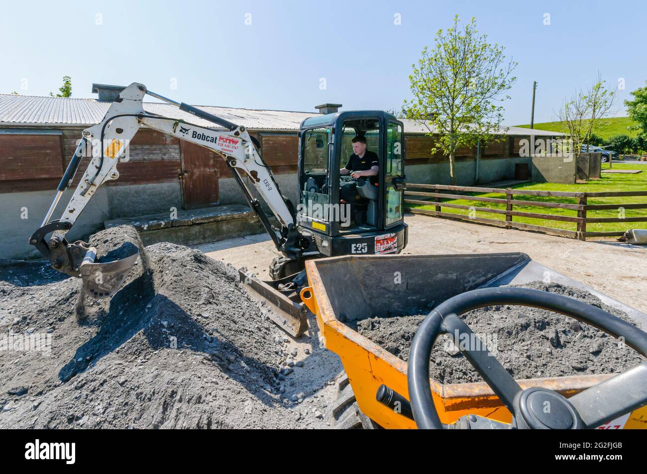 Bobcat E25 mini-digger excavator loads crushed blinding aggregate stones  into a yellow dump truck at a building site on a farm Stock Photo - Alamy