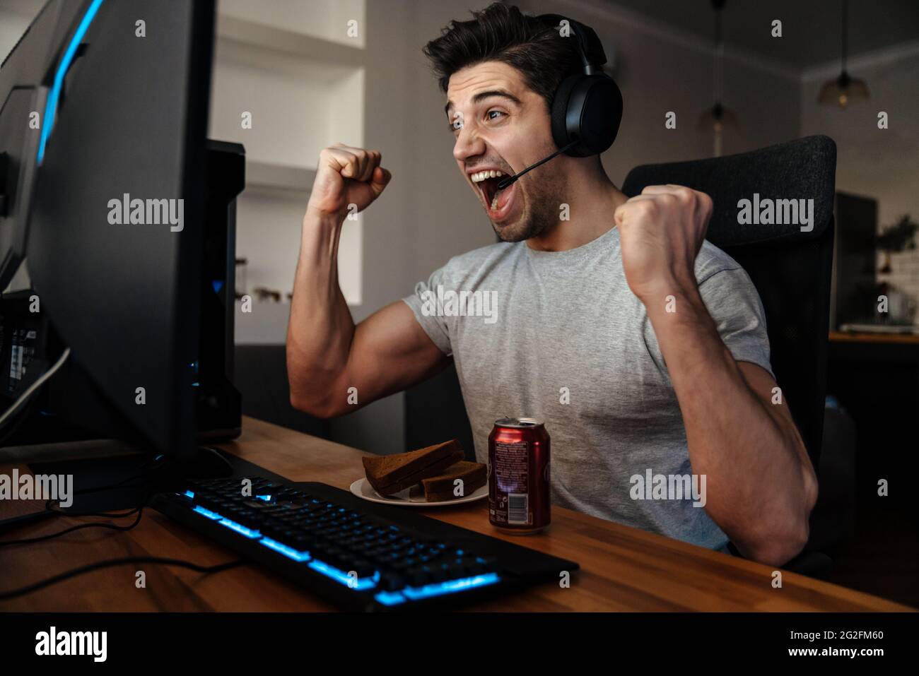 Excited guy in headphones making winner gesture while playing video ...
