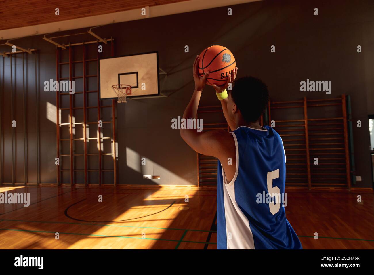 Mixed race male basketball player practicing shooting with ball Stock