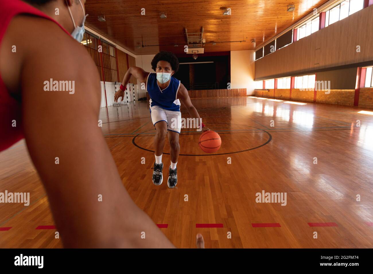 Two diverse male basketball players wearing face masks and practice