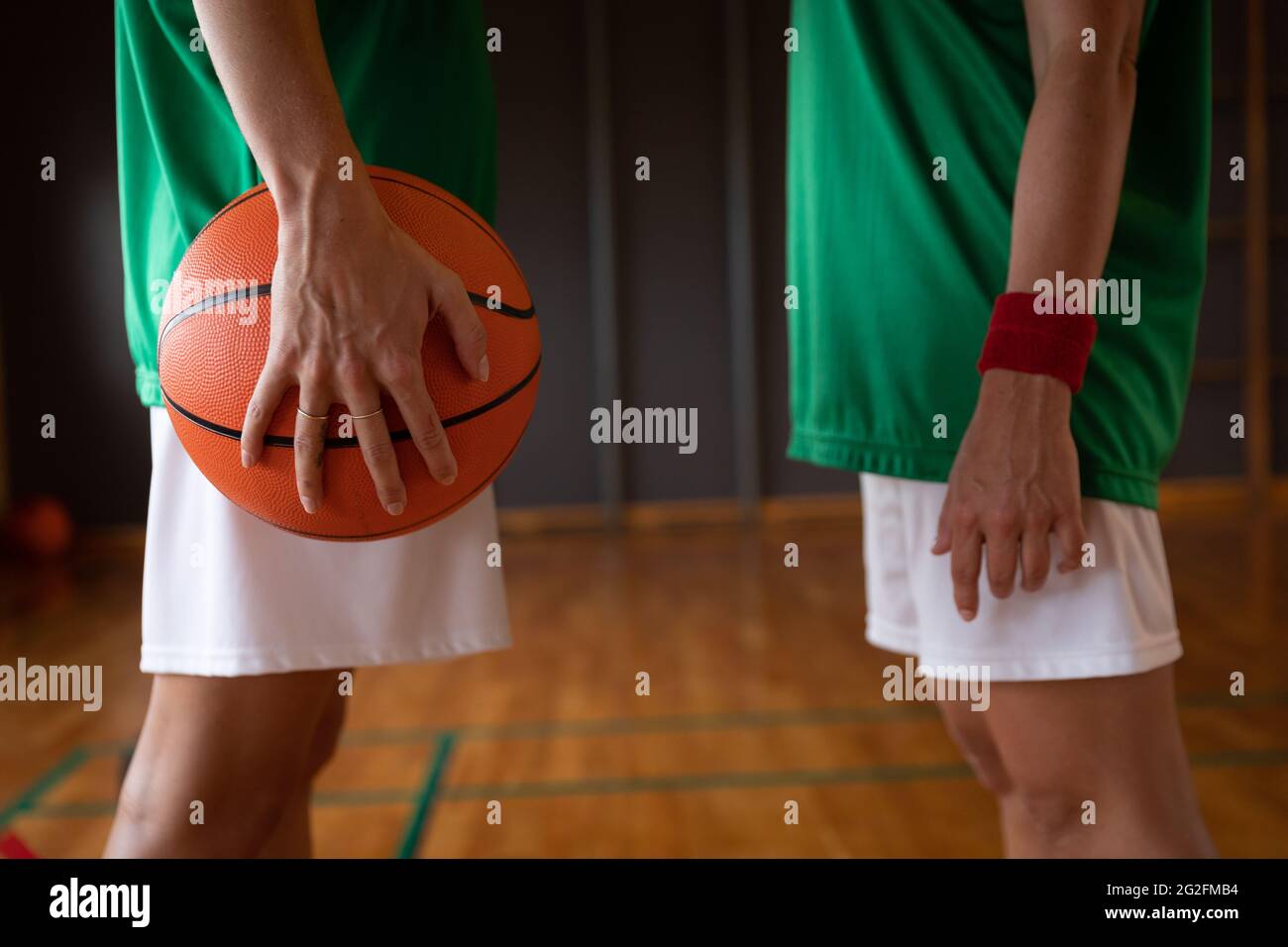 Two diverse female basketball players wearing sportswear and holding