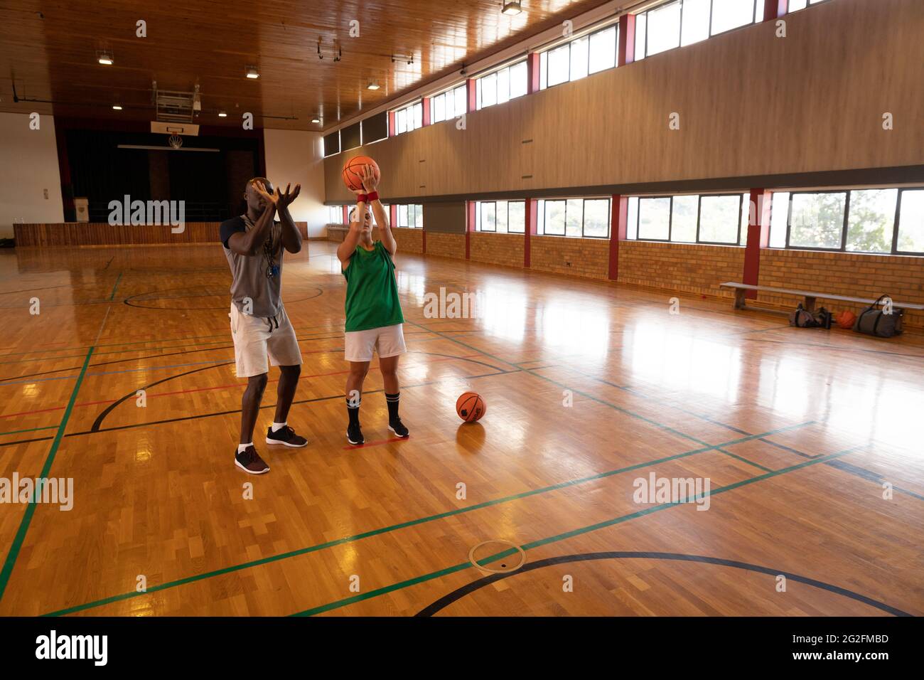 Caucasian female basketball player and coach practicing shooting with