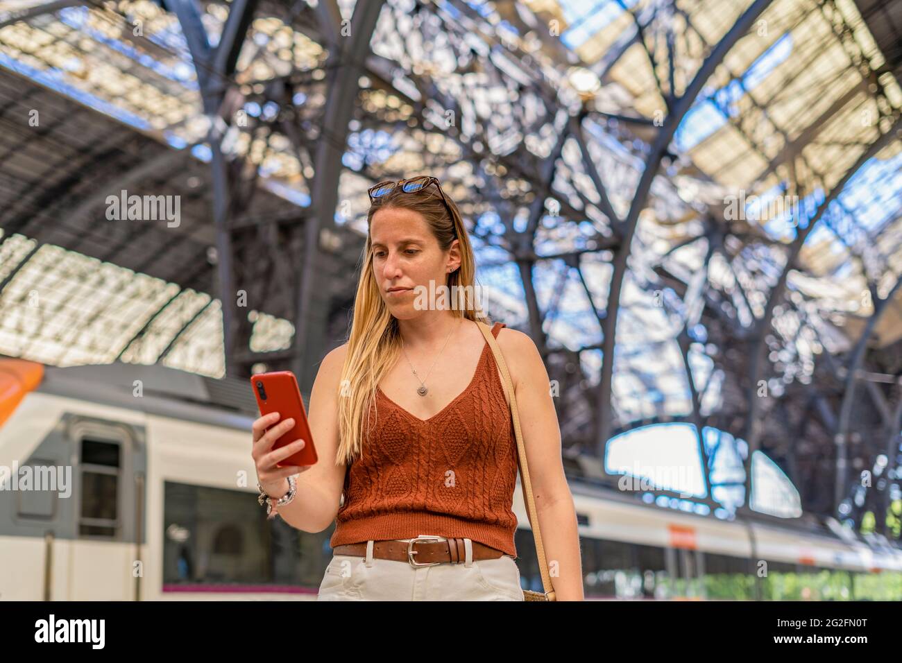 Young woman waiting at train station platform using smart phone Stock Photo