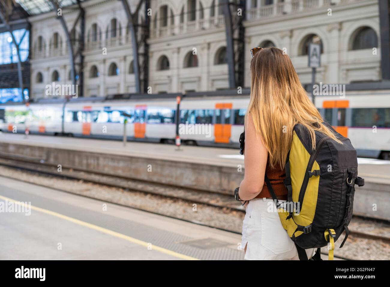 Young woman with backpack waiting at train station platform Stock Photo
