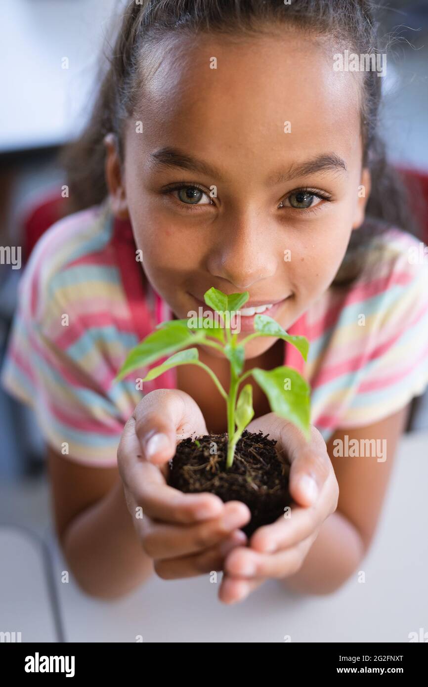 Portrait of african american girl holding a plant seedling in the class at school Stock Photo
