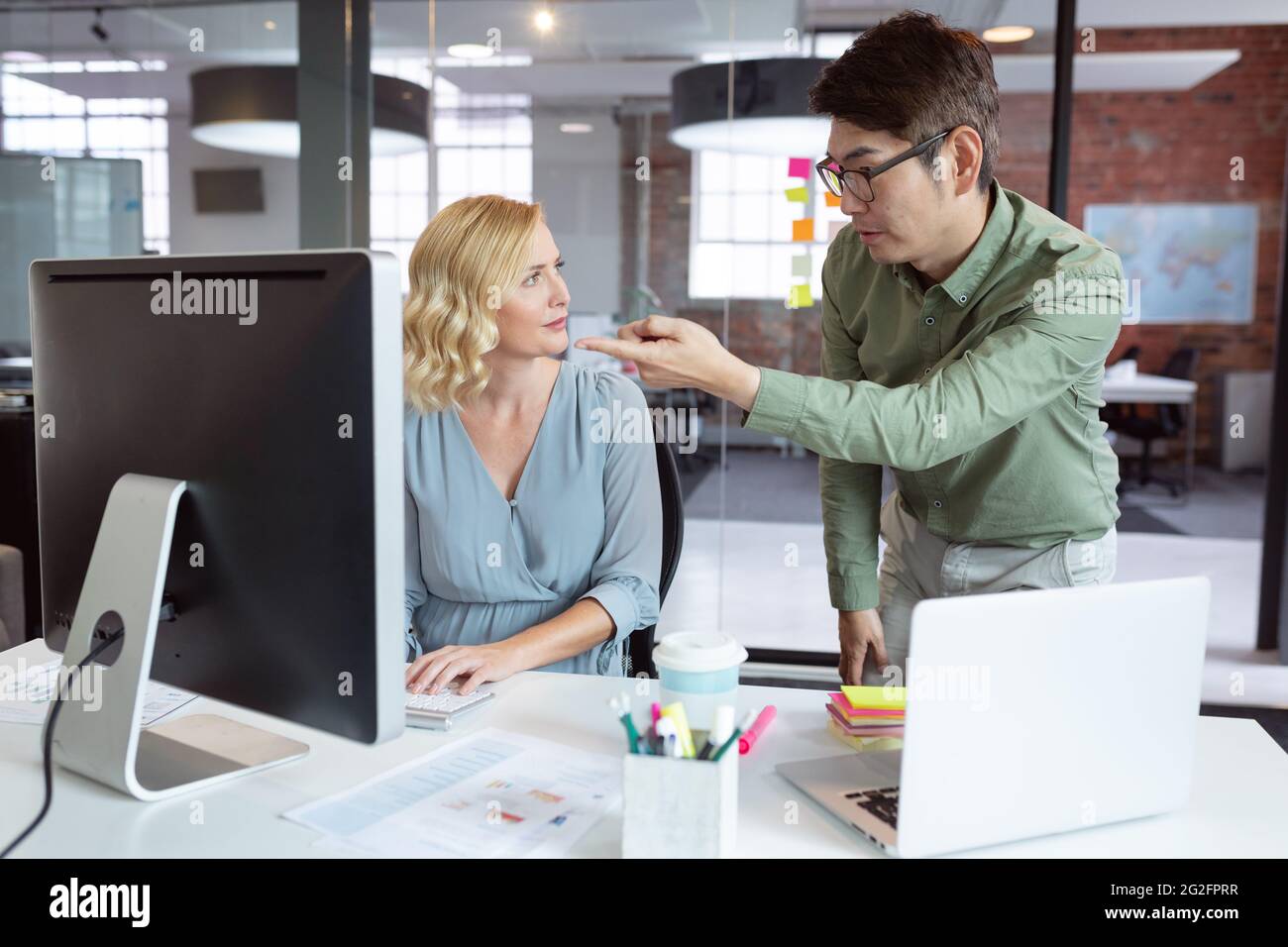 Diverse male and female colleague looking at computer screen and ...