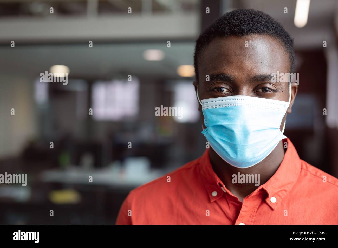 Portrait of african american businessman wearing face mask looking to ...