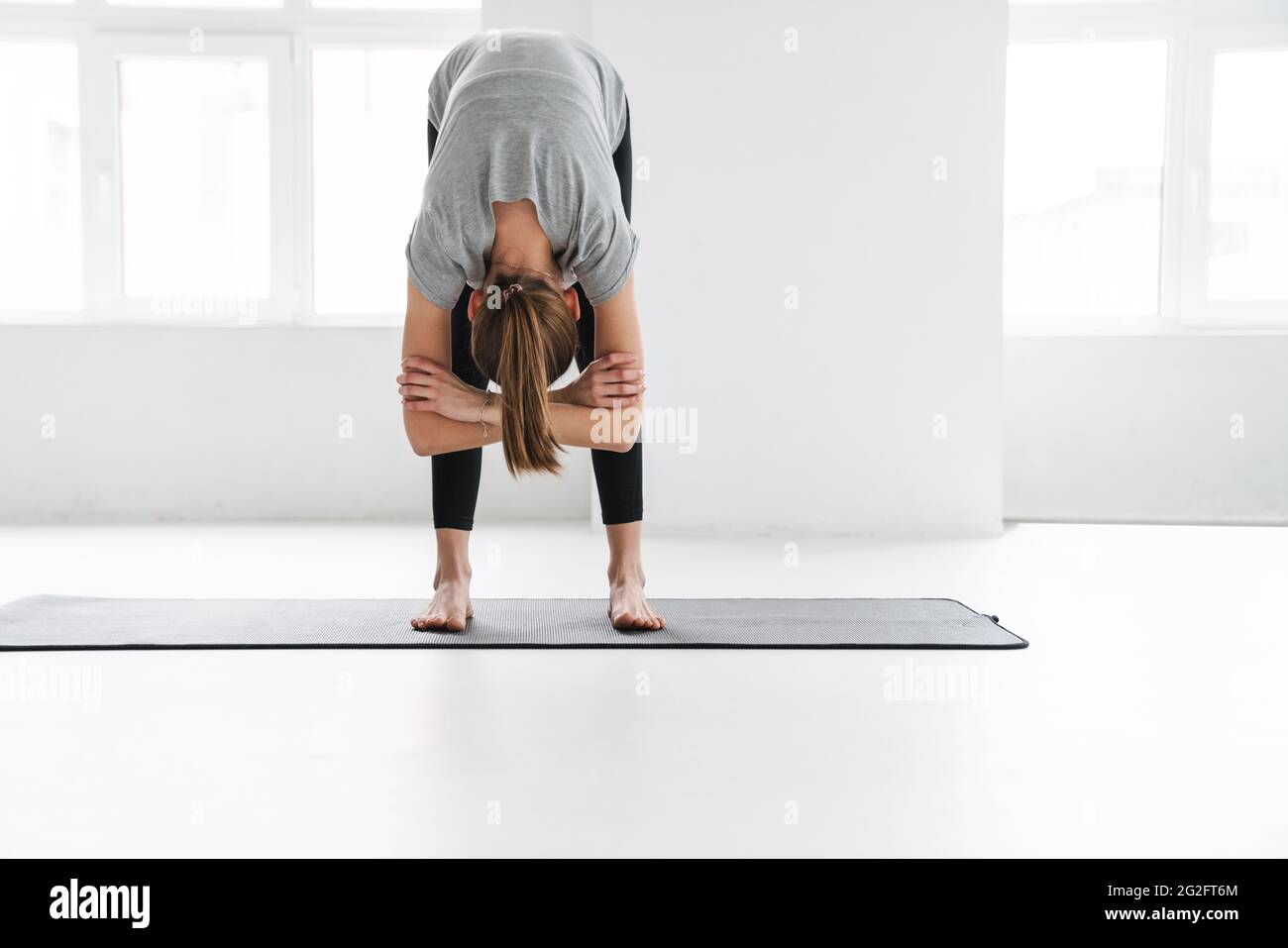 Healthy attractive young yoga woman stretching on a fitness mat in ...
