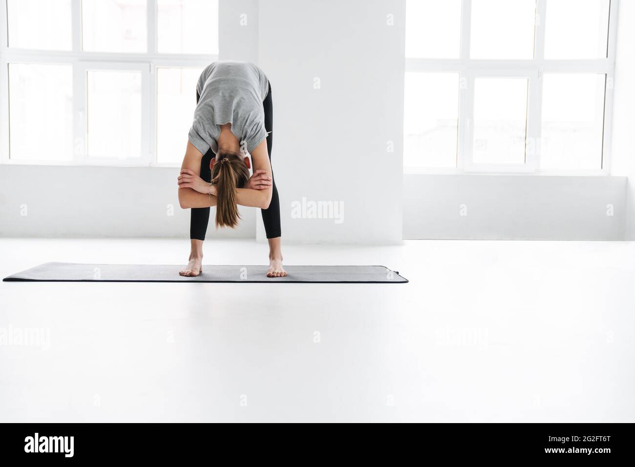 Healthy attractive young yoga woman stretching on a fitness mat in ...