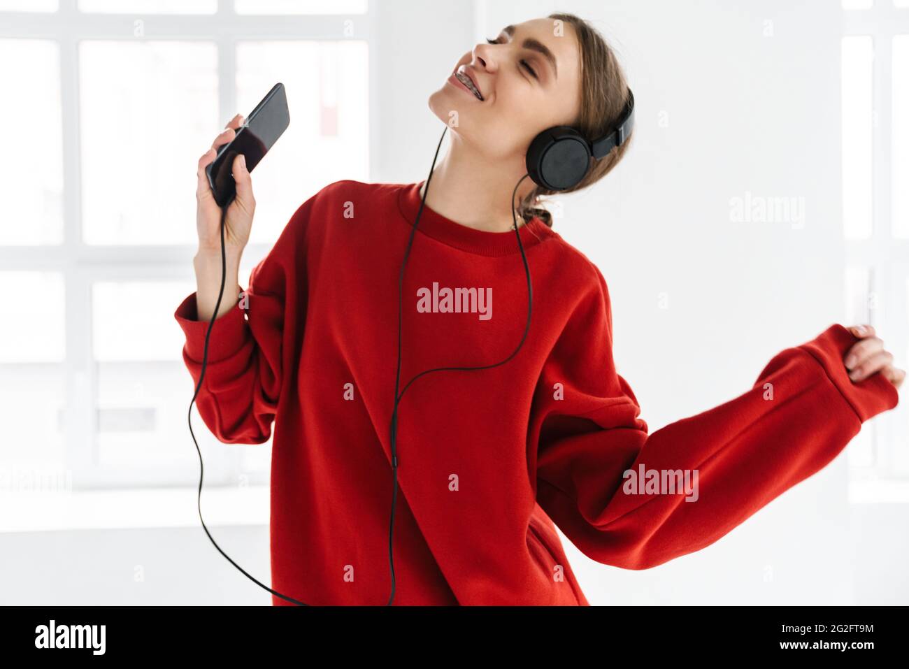 Happy woman dancing while listening music with headphones and ...