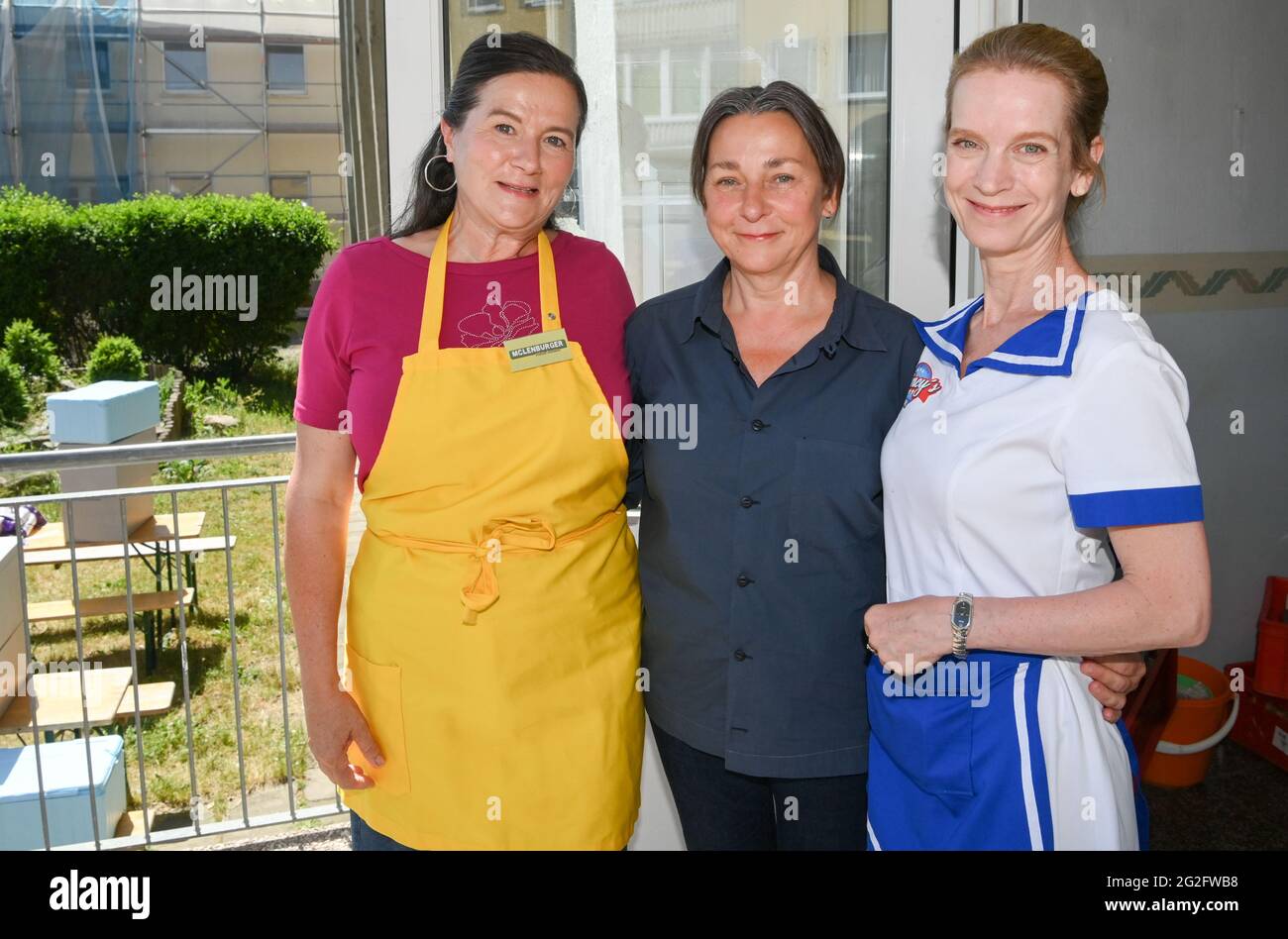 Pasewalk, Germany. 10th June, 2021. Actresses Anne-Kathrin Gummich (l-r), Steffi Kühnert and Judith Engel stand on set during filming for the TV movie 'McLenBurger - Once in a Lifetime'. In the ARD Degeto comedy, the once youngest canteen manager in GDR times opens a restaurant with homemade burgers and other regional specialties. She faces competition from a burger chain in the region. Filming takes place in Mecklenburg-Western Pomerania and Berlin. Credit: Jens Kalaene/dpa-Zentralbild/dpa/Alamy Live News Stock Photo