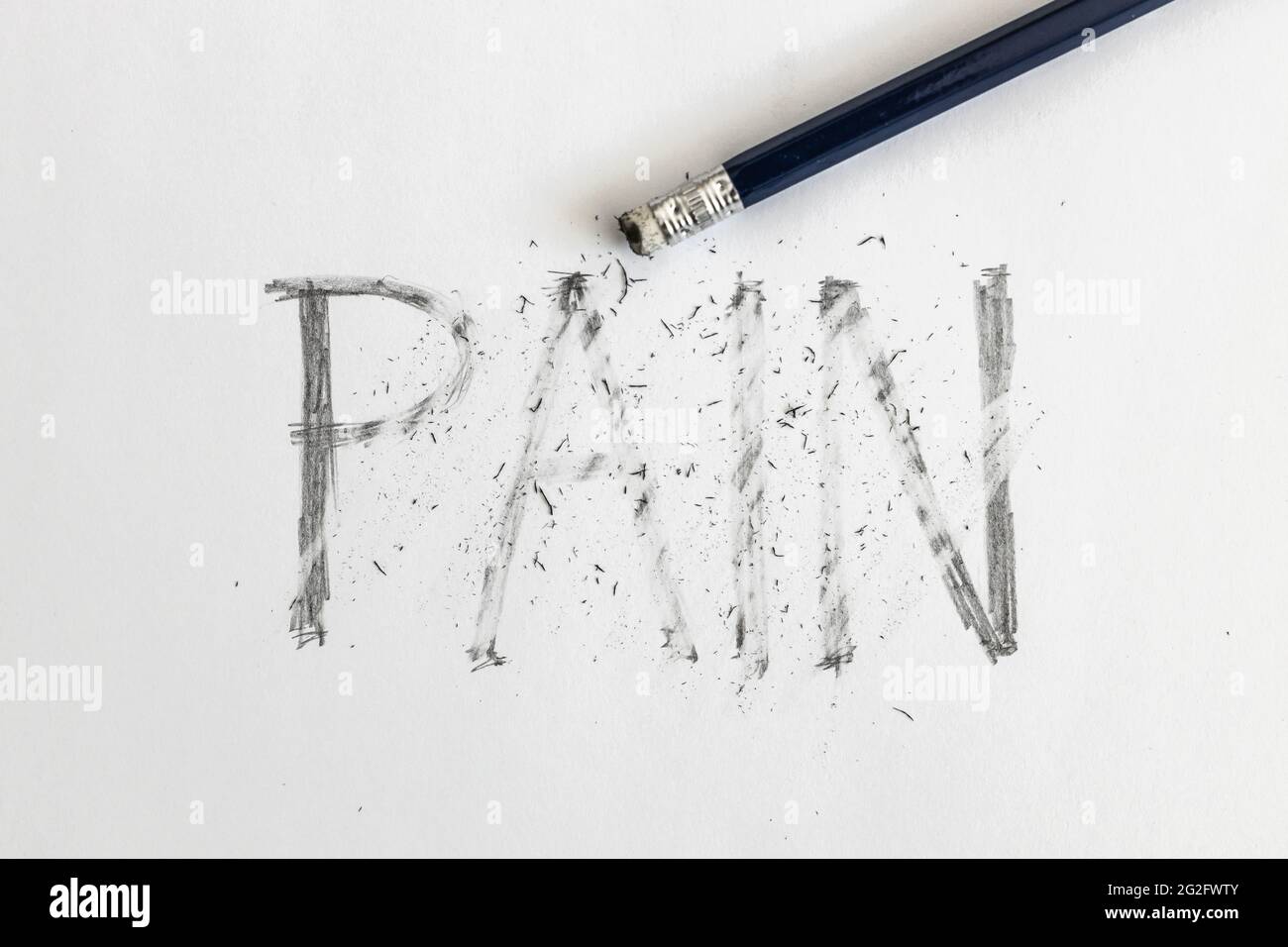 Erasing pain. Pain written on white paper with a pencil, erased with an eraser. Symbolic for overcoming pain or treating pain. Stock Photo