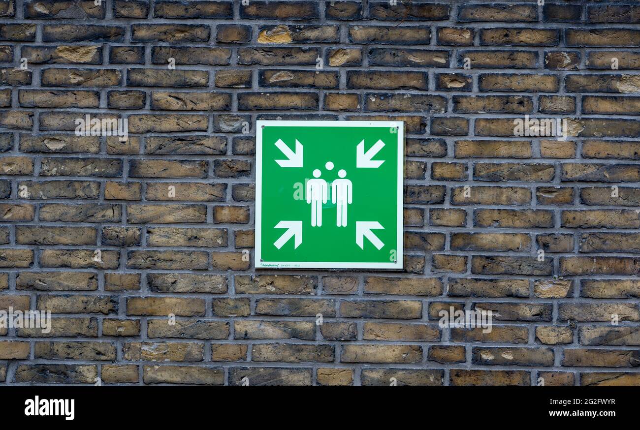 Sign for a fire assembly point installed on a brick wall. Stock Photo