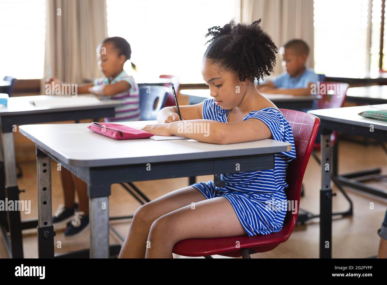 African american girl studying while sitting on her desk in the class ...