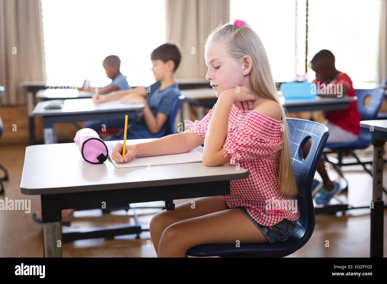 Caucasian girl studying while sitting on her desk in the class at ...
