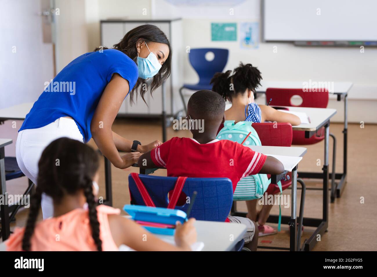 African american female teacher wearing face mask teaching african