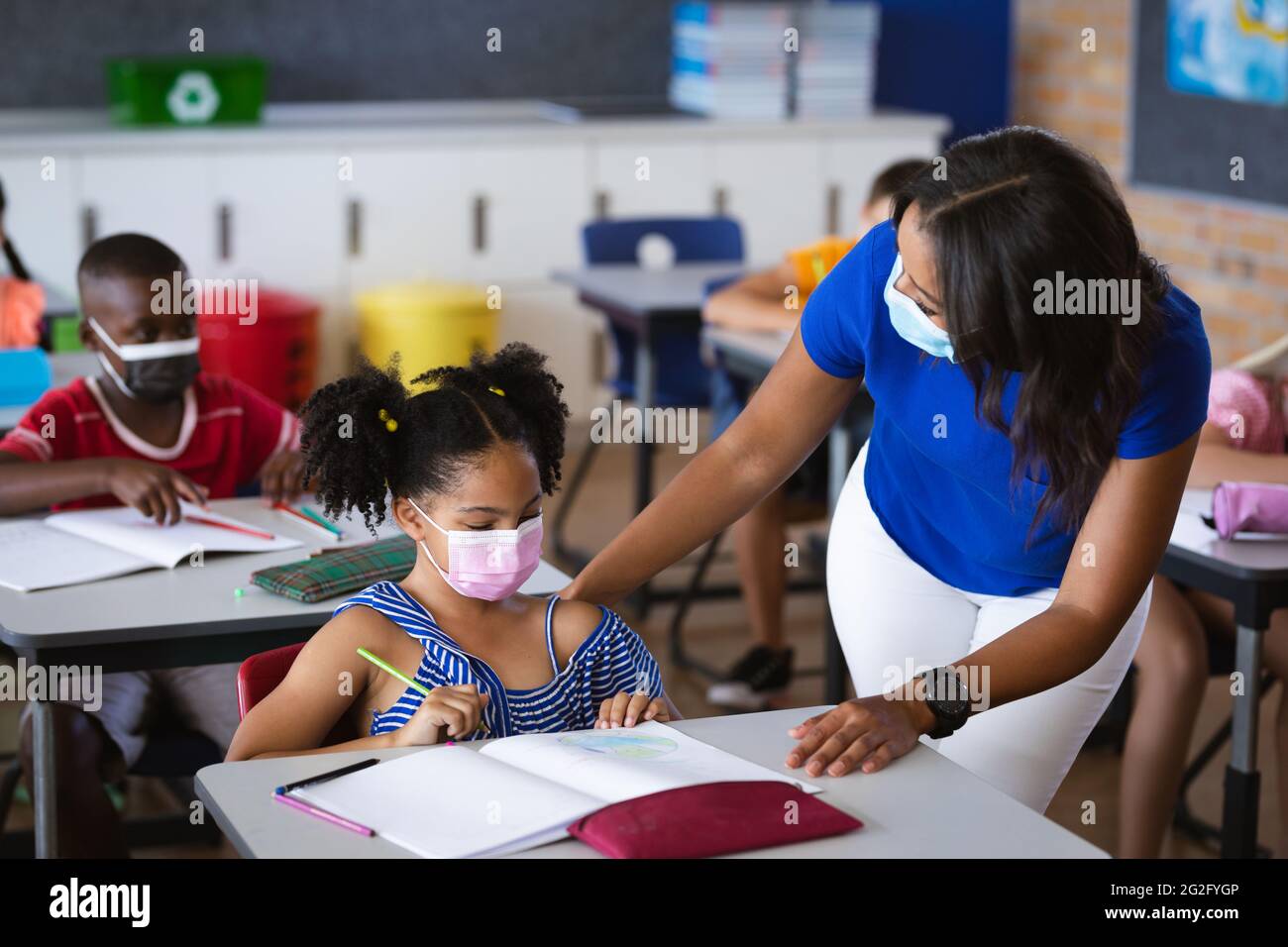 African american female teacher wearing face mask teaching african