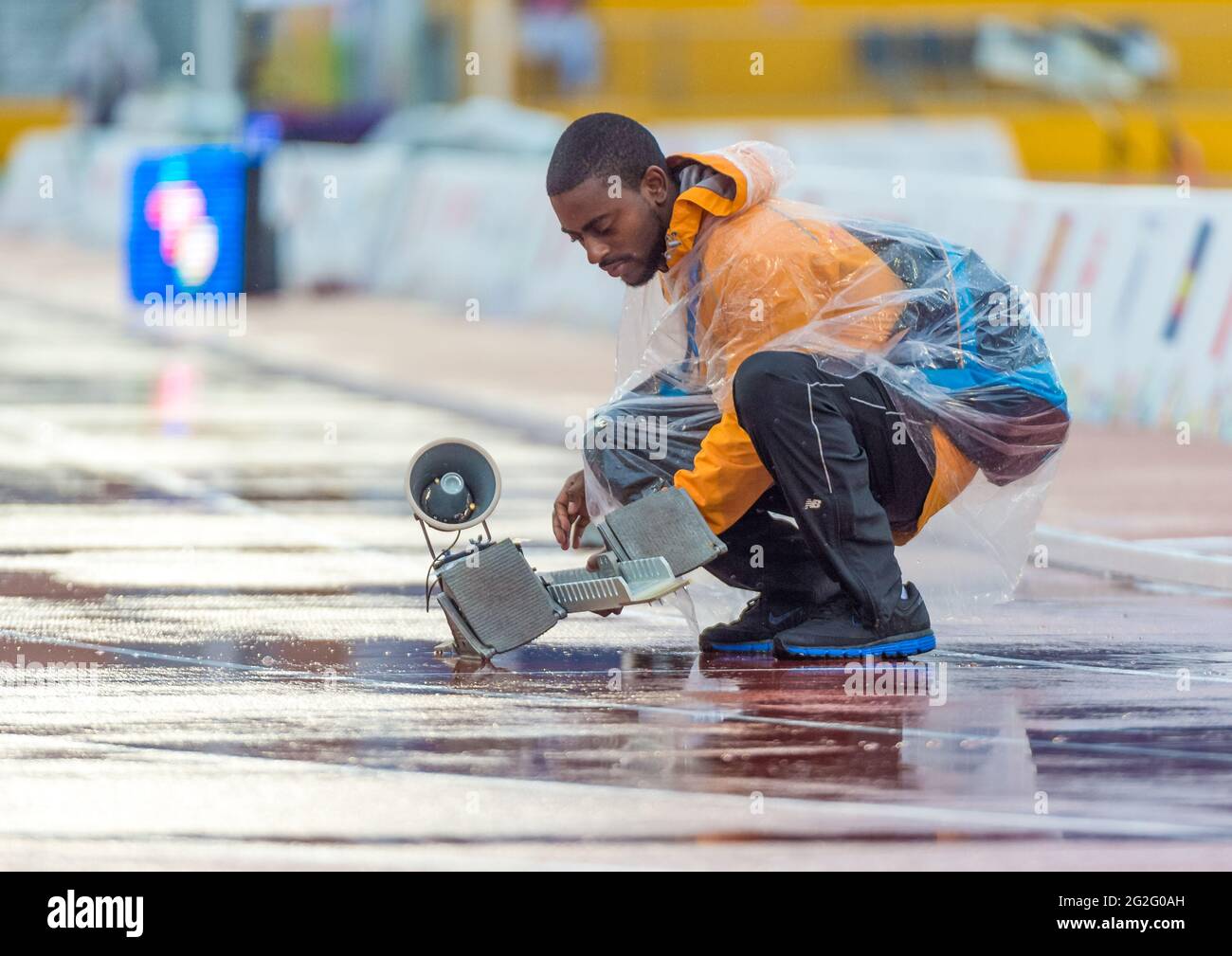 Volunteer fixing the starting blocks on a wet running track at the 2015 Parapan American Games. Starting blocks are a device used by sprint athletes t Stock Photo