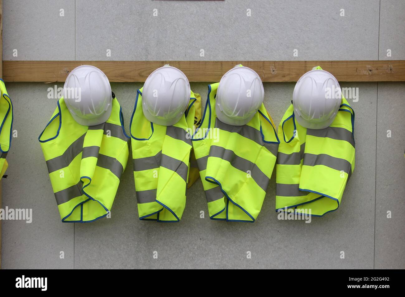 Row of hard hats and child sized high vis vests Stock Photo Alamy