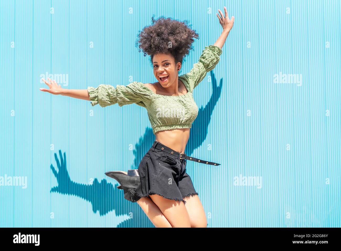 happy woman with afro hair jumping for joy Stock Photo