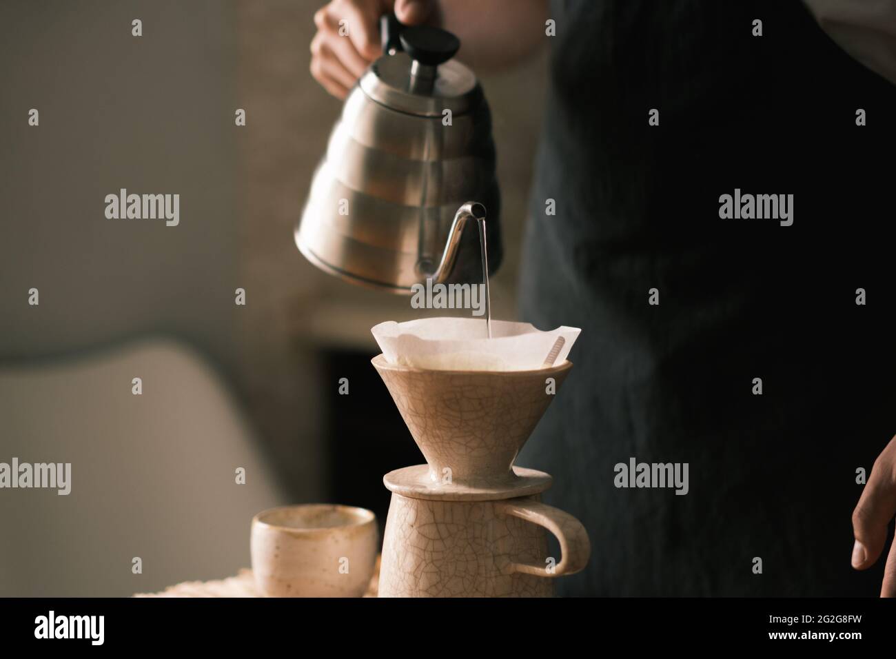 Brewing pourover coffee in the kitchen, pouring hot water on the Stock Photo