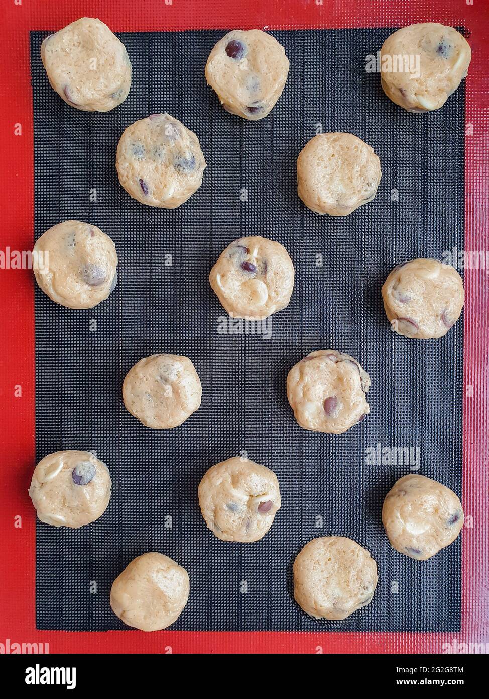 15 round shape cookie dough on the black silicone baking mat Stock Photo