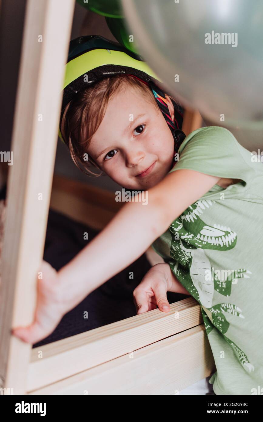 5 years boy playing in his room, wearing green t-shirt with dinosaurus print and dino helmet Stock Photo