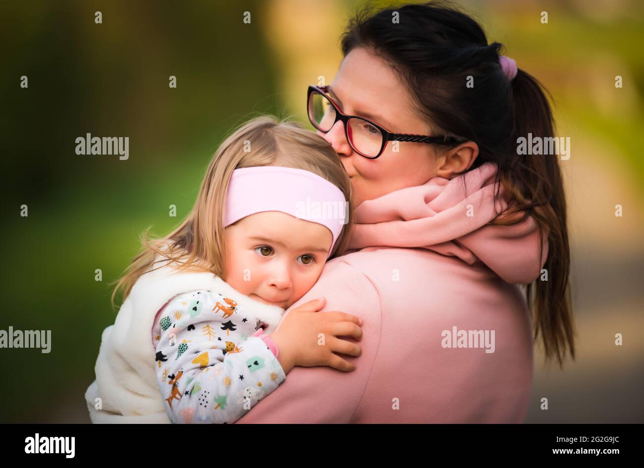 Mother holding and hugging child walking in nature outside. Stock Photo