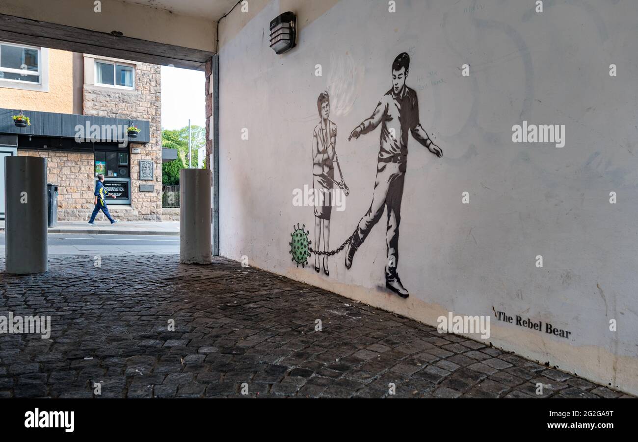 Rebel Bear graffiti on alley wall with a conceptual depiction of Covid-19 Coronavirus, a man wearing a ball and chain & Nicola Sturgeon with bolt cutters representing the possible end of lockdown restrictions during the pandemic, Canongate, Edinburgh, Scotland, UK Stock Photo