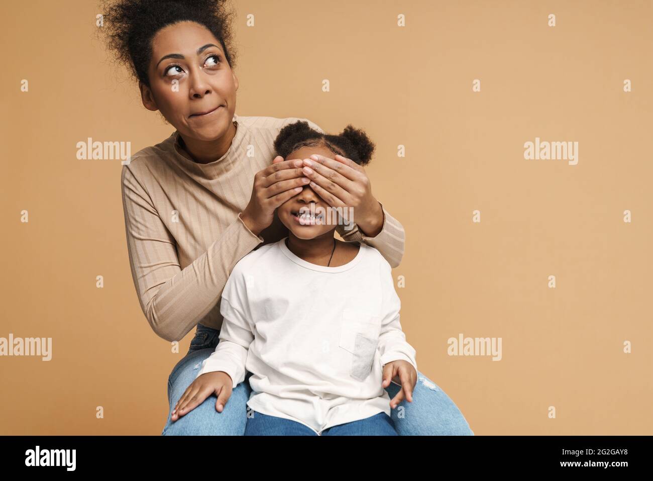 Happy black mother and daughter covering eyes while making fun isolated