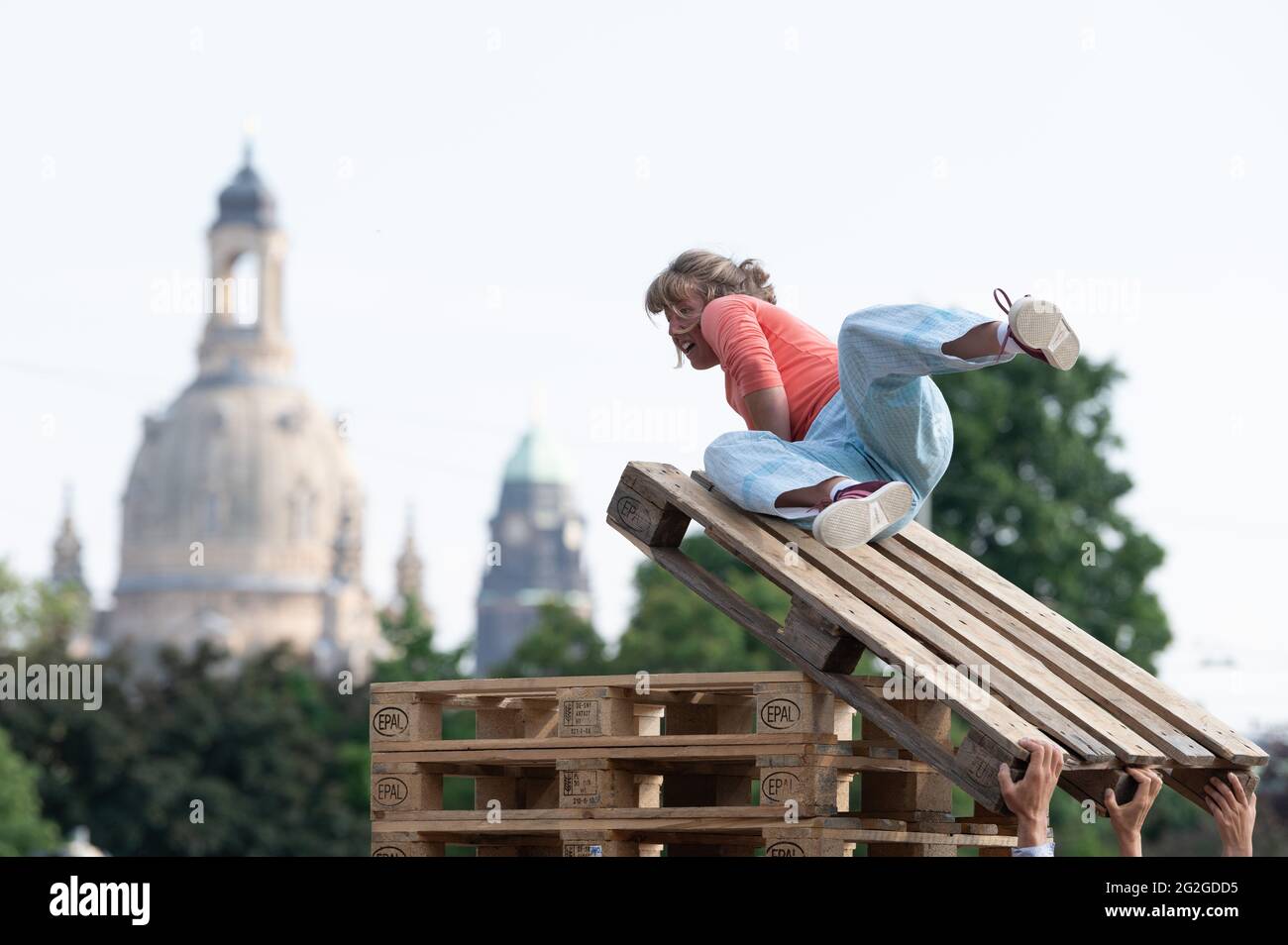 Dresden, Germany. 11th June, 2021. An artist of the small circus group  "FahrAway" from Switzerland lies on a stack of Euro pallets during a  performance in front of the backdrop of the