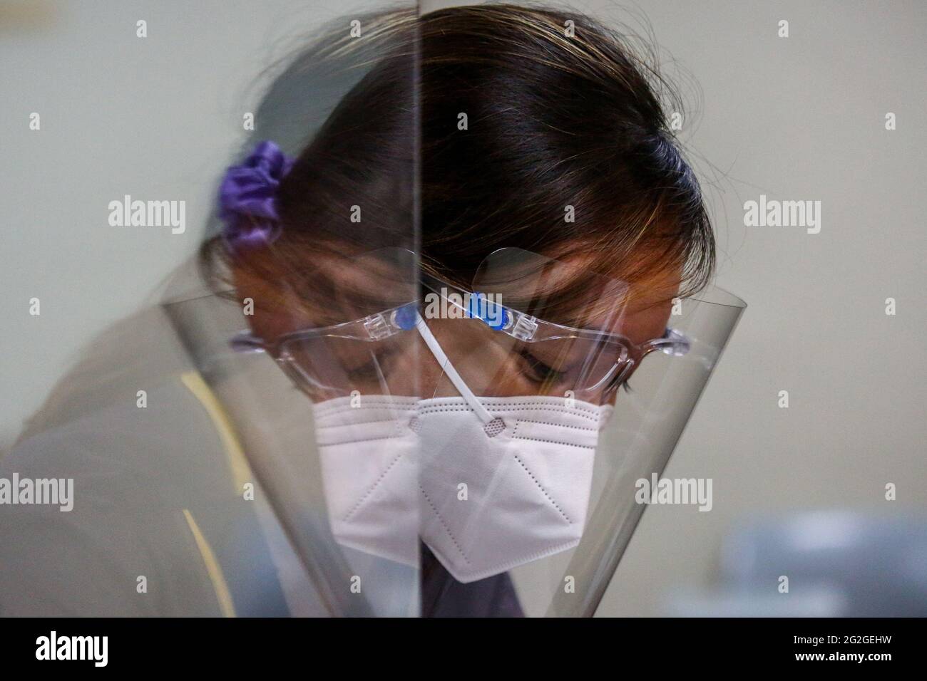 Manila, Philippines. June 10th 2021. A medical student is reflected on a plastic barrier during a face-to-face class at the University of Santo Tomas. The university started its limited face-to-face classes after the government allowed the resumption hands-on training and laboratory classes in campuses while observing health protocols to prevent the spread of the coronavirus disease. Stock Photo