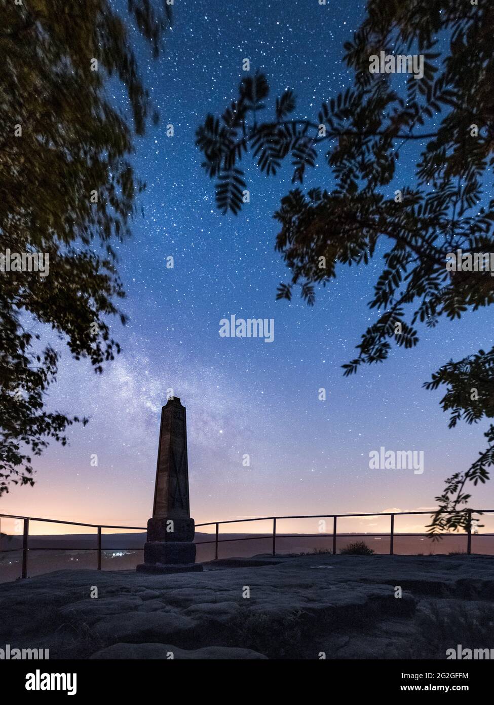 Historical obelisk under the starry sky with the Milky Way on the Lilienstein in the Elbe Sandstone Mountains. Stock Photo