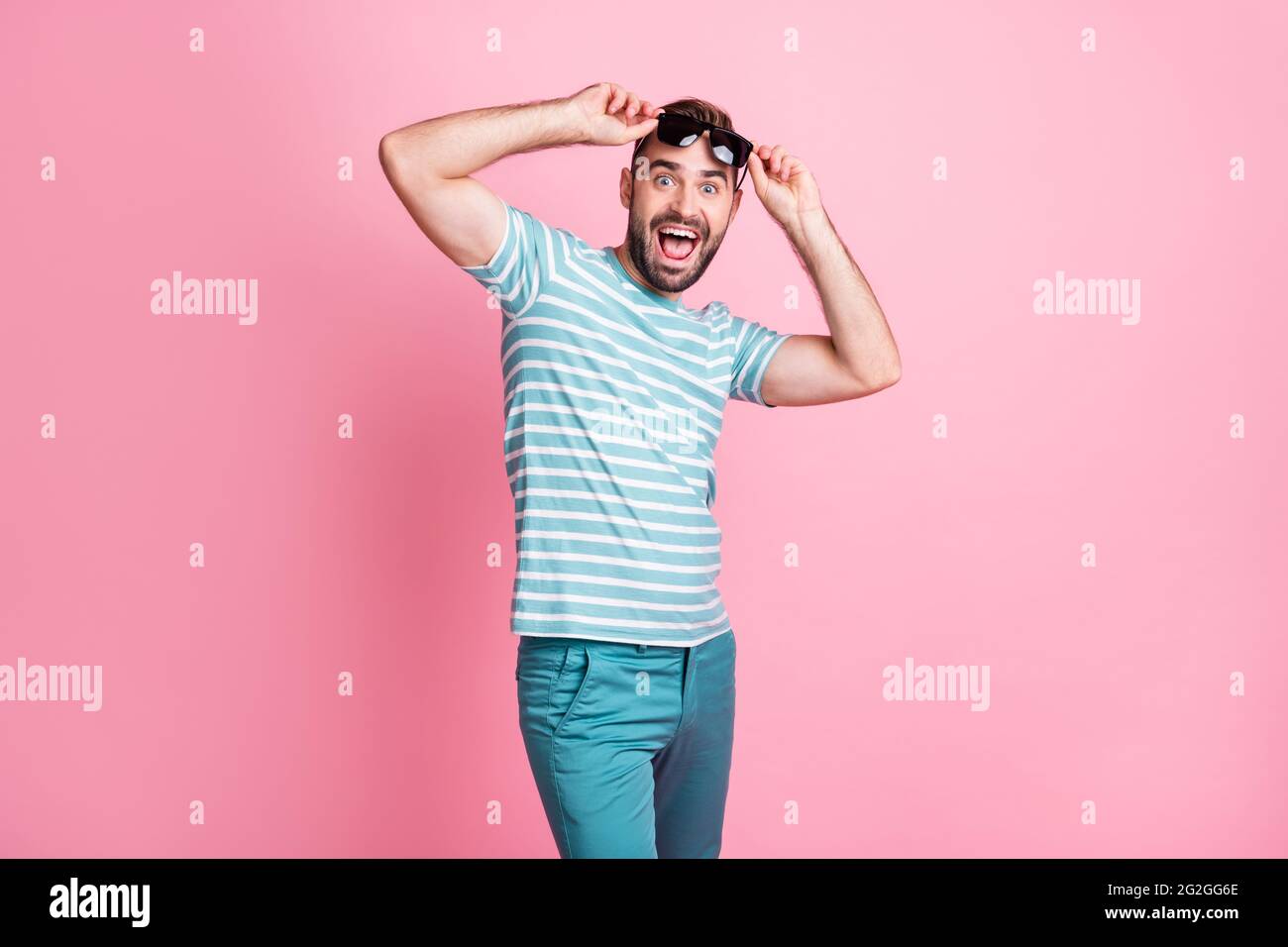 Portrait of nice cheerful lucky amazed guy wearing touching sunglasses having fun news reaction isolated over pink pastel color background Stock Photo