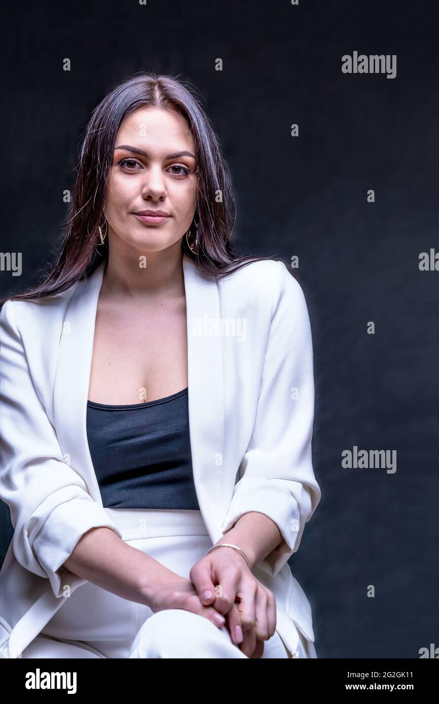 Portrait of woman dressed in office style. Brunette girl in white business suit in studio Stock Photo