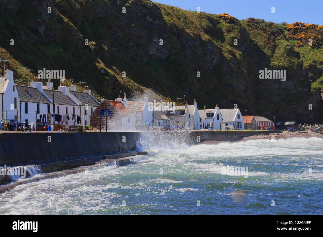 Waves crashing into Pennan, a small village in Aberdeenshire, Scotland. Consisting of a small harbour and a single row of homes. Stock Photo