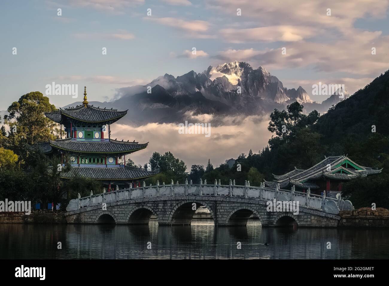 The Moon Embracing Pavilion, Suocui Bridge and Black Dragon Pool against the backdrop of the Jade Dragon Snow Mountain in Lijiang, China Stock Photo