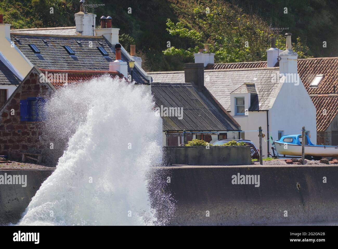 Waves crashing into Pennan, a small village in Aberdeenshire, Scotland. Consisting of a small harbour and a single row of homes. Stock Photo