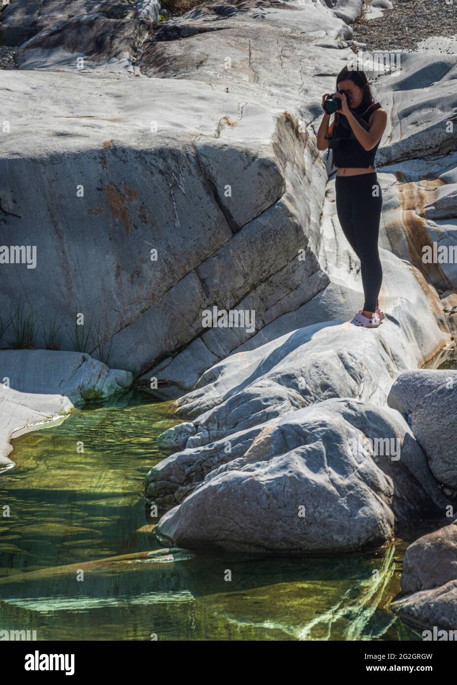 Impressions from Lavertezzo in the Verzasca Valley, Locarno district, Canton Ticino in Switzerland: popular excursion destination for hiking, river diving and swimming. Young woman taking photos. Stock Photo