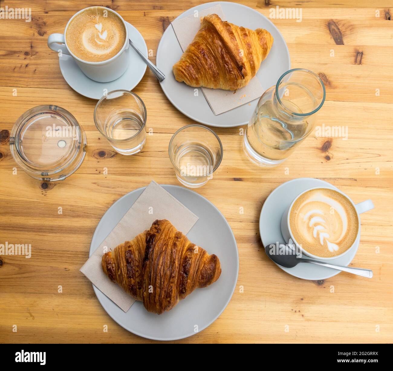 Cups of latte coffee and croissants on wooden table Stock Photo