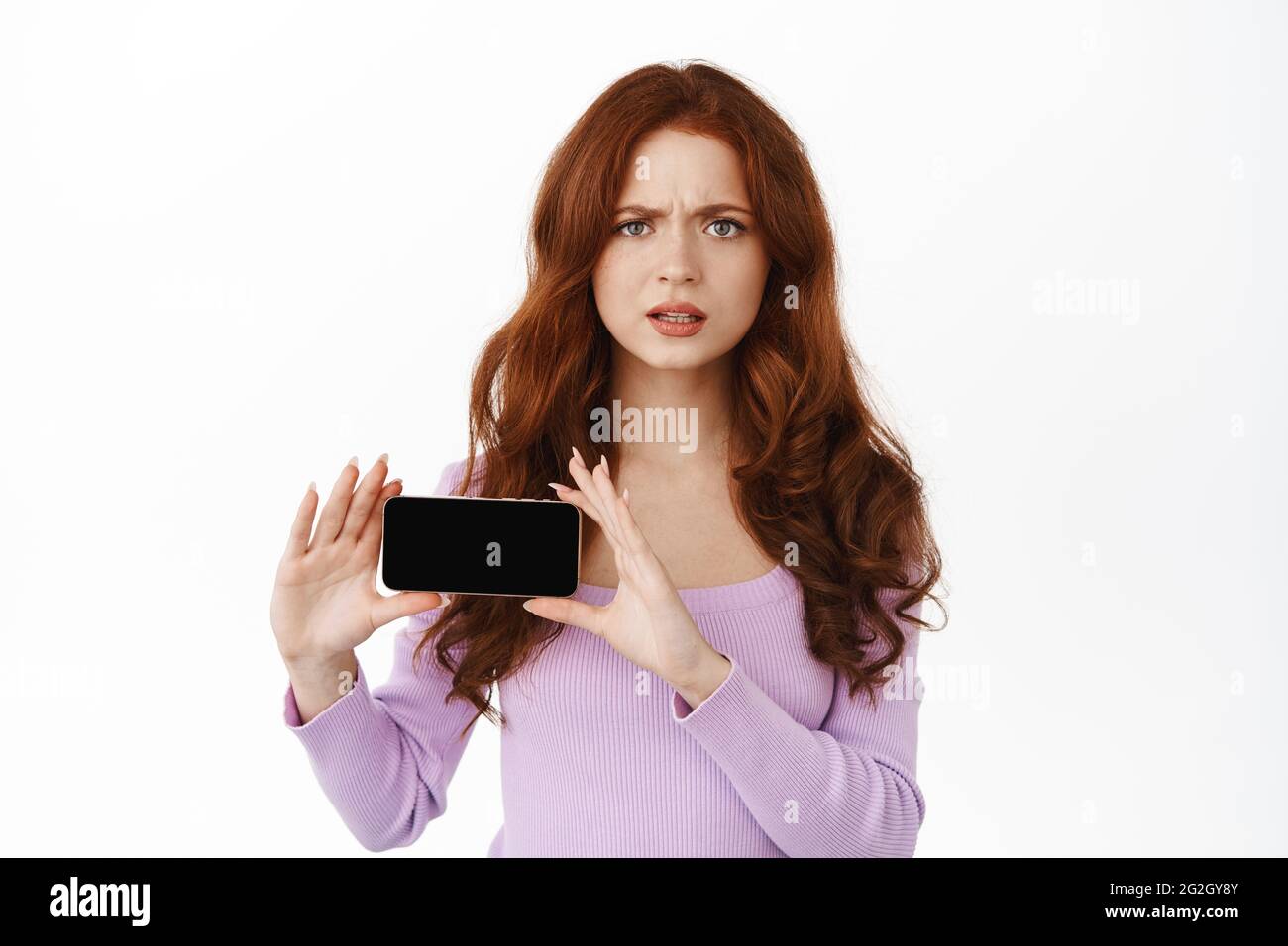 Frustrated And Disappointed Redhead Woman Frowning Showing Smartphone Horizontal Screen 2535
