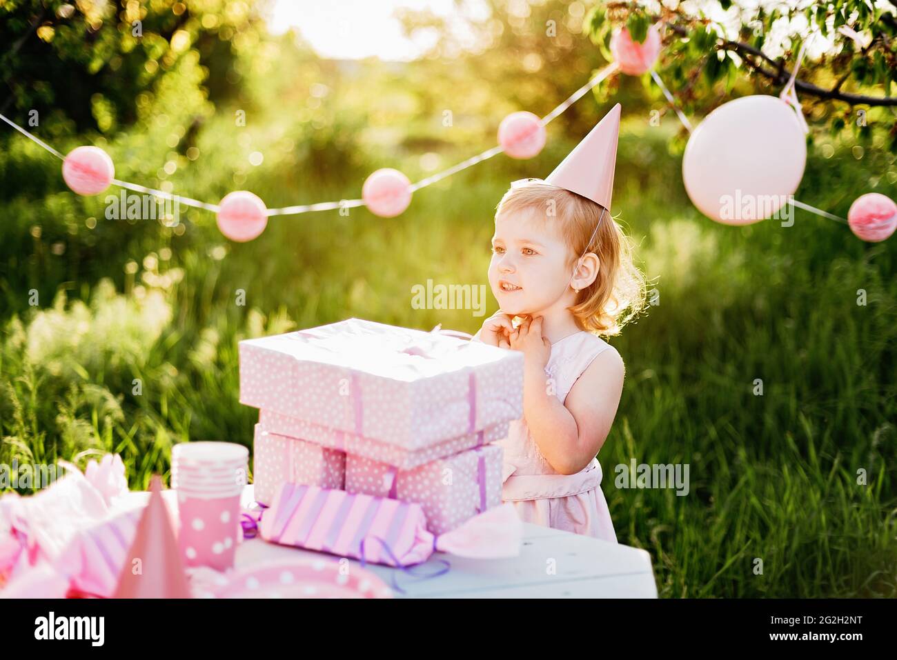 Happy birthday little girl with gift box in beautiful garden. child eat happy birthday rose