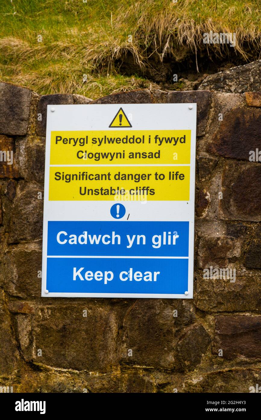 sign in welsh and English Significant danger to life unstable cliffs at Nefyn, Llyn Peninsula, Wales, UK. This happened in April 2021, this image take Stock Photo